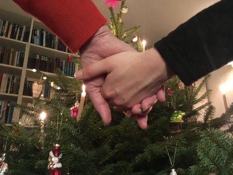 To personer holder hinanden i hænderne imens de danser rundt om juletræet