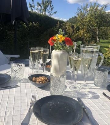 Et flot udendørs dækket bord haven med tallerkner, champagne og friske sommerblomster 