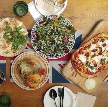 Lækker pizza og salater står klar på bordet til gæsterne i spisefællesskaber kommer på besøg