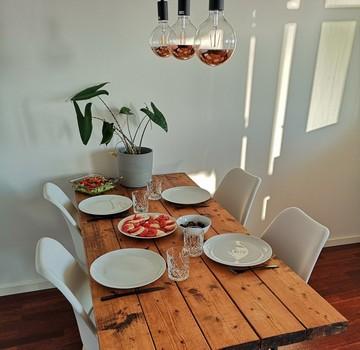 Et flot plankebord med tallerkner, glas og lækre salater står klar til at madklubbens gæster kommer på besøg